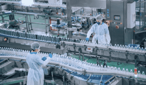 Two factory workers inspect water bottles on a factory floor